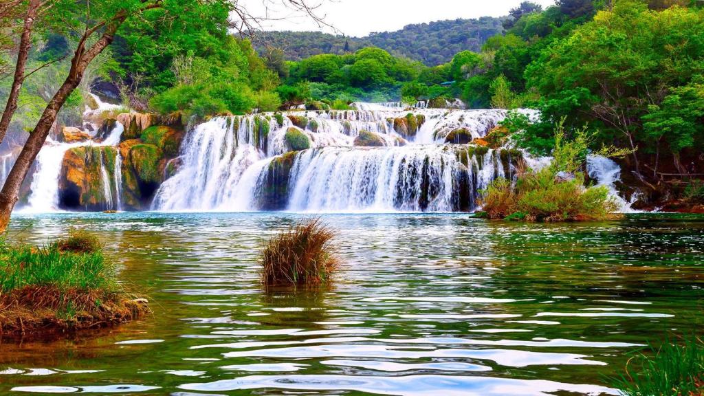 una cascada en medio de un cuerpo de agua en Matanovi dvori-Krka National Park en Lozovac