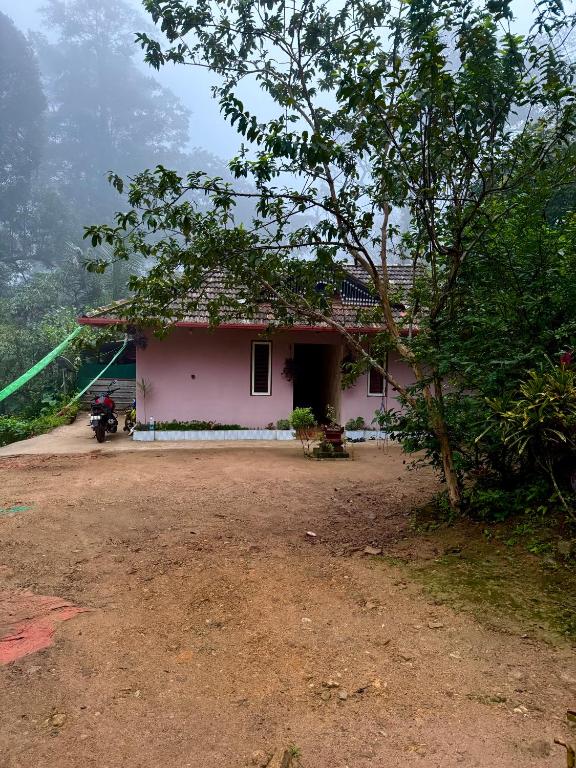 a pink house on top of a mountain at River stream Nest homestay in Madikeri