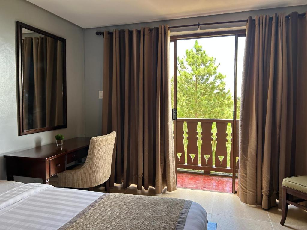 a bedroom with a bed and a desk and a balcony at Crosswinds Swiss Studio Double Suite in Ulot