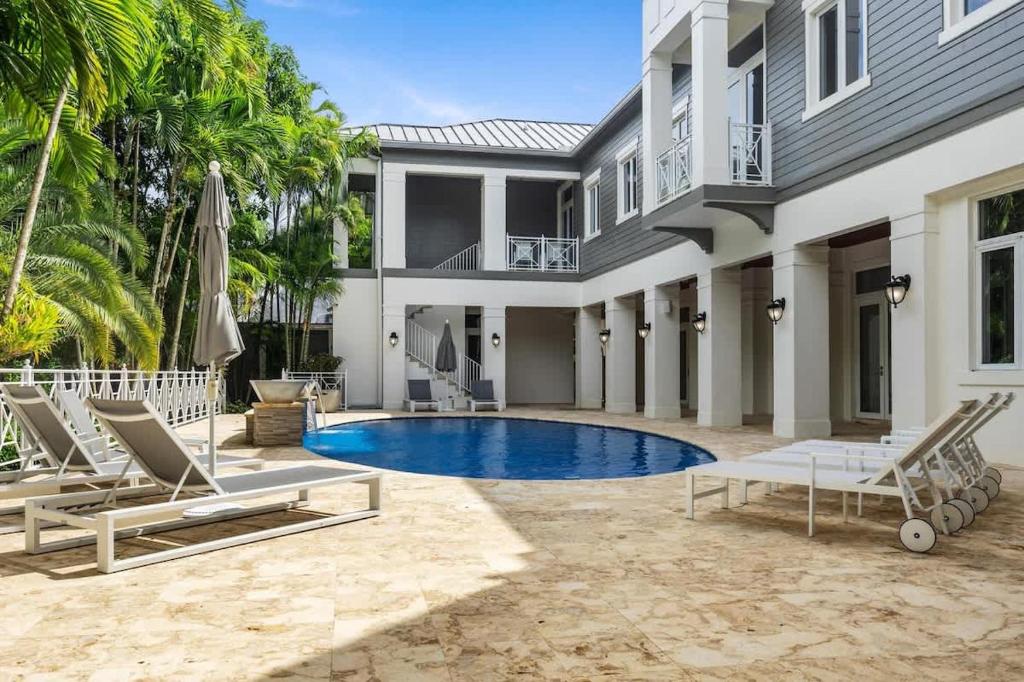 a house with a swimming pool and two lounge chairs at New Luxe Super Villa by The Glam Homes in Plantation