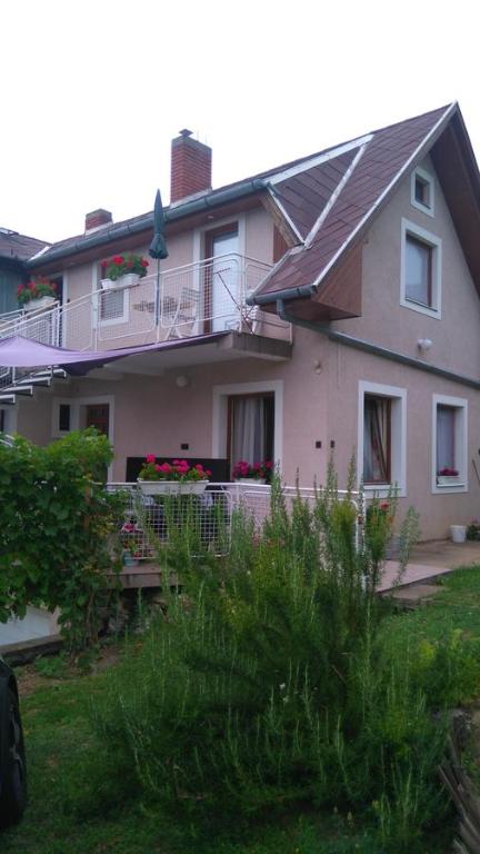 Casa de color rosa con porche y balcón en Bertalan Apartman en Vonyarcvashegy