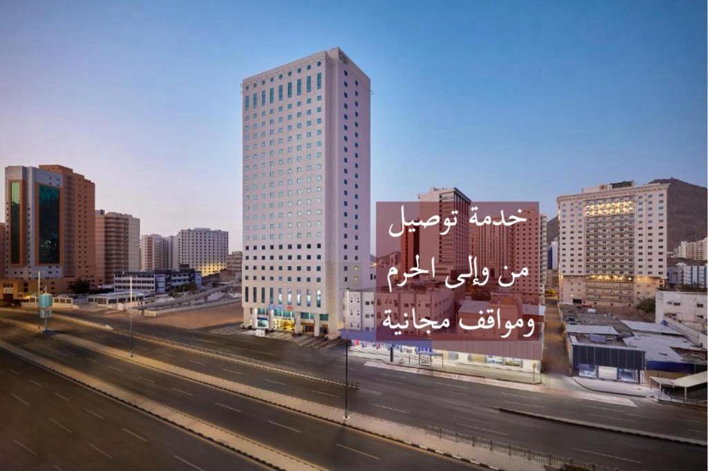 une ville avec un grand bâtiment avec des inscriptions dessus dans l'établissement Makarem Al Bait Al Azizia Hotel, à La Mecque