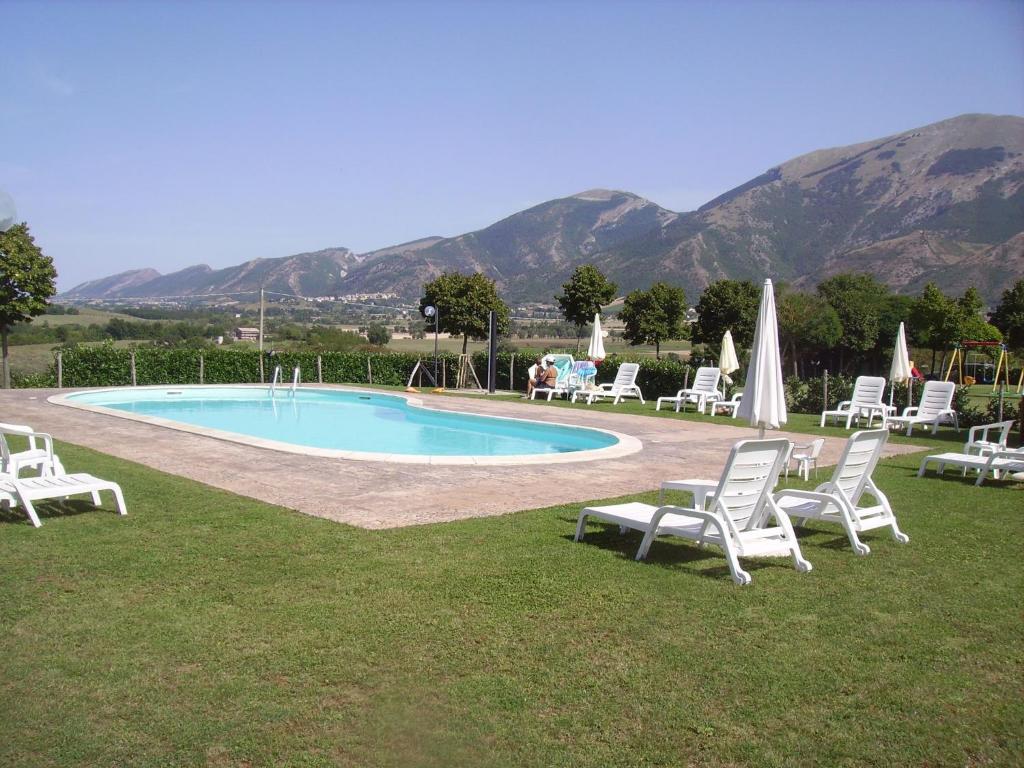 eine Gruppe von Stühlen und ein Pool mit Bergen im Hintergrund in der Unterkunft Appartamenti Albarosa by Holiday World in Sigillo
