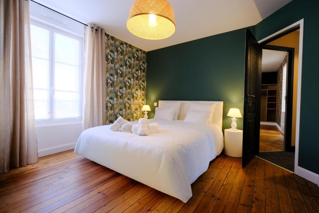 a bedroom with a white bed and a green wall at LOGIS des COEVRONS in Évron