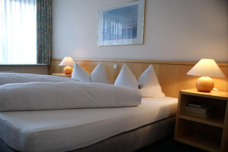a hotel room with a large bed with white pillows at Hotel Herian in Parsdorf