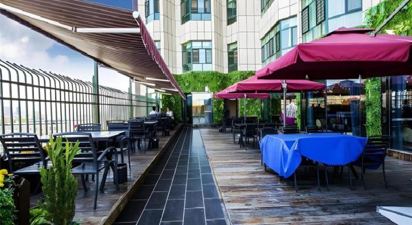 a row of tables and chairs with umbrellas on a patio at Metropolo Hotel Yining Development Zone Hanma Building in Kipekyüzi