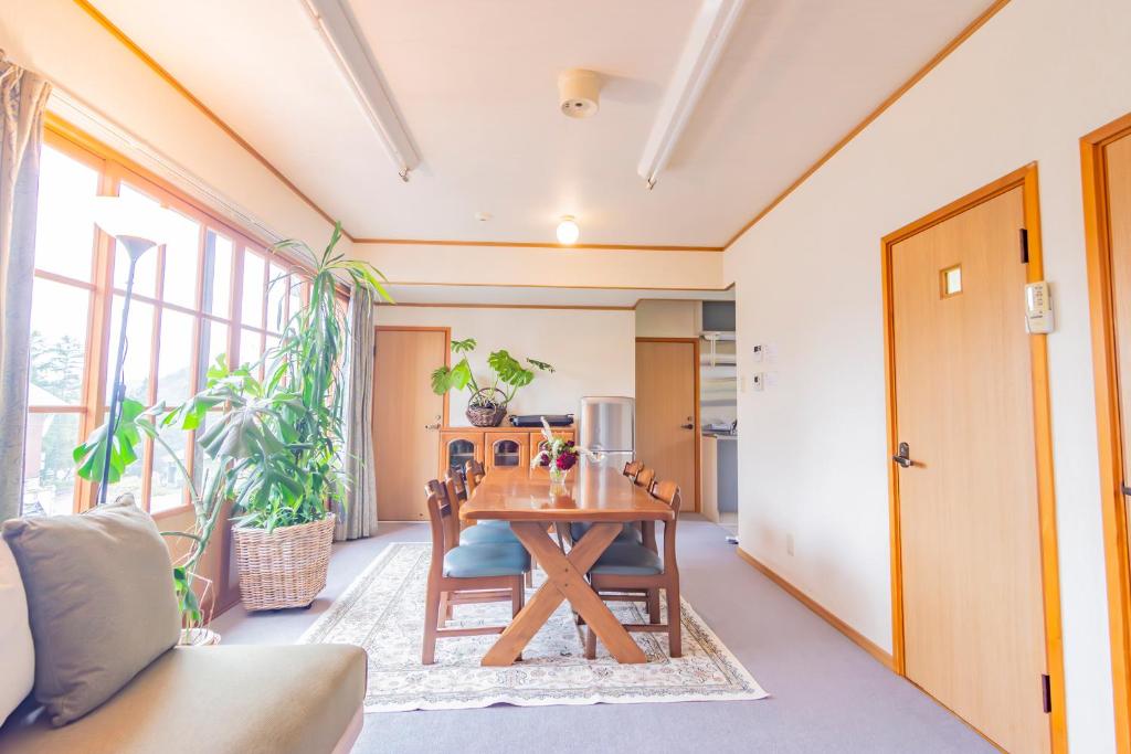 a dining room with a wooden table and chairs at The Snowfront Apartment Nabe Sun -HAKUBA GORYU- in Hakuba