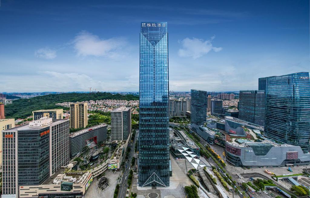 a tall glass skyscraper in the middle of a city at Mehood Elegant Hotel Panyu Chimelong Wanbo in Guangzhou