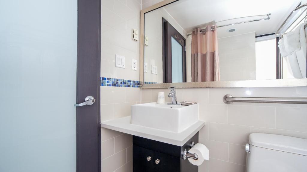a white bathroom with a sink and a mirror at Hotel Richland LES in New York