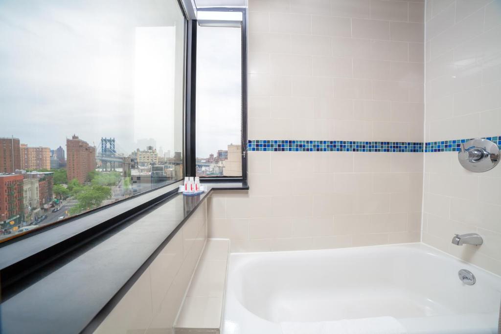 a bathroom with a bath tub and a window at Hotel Richland LES in New York