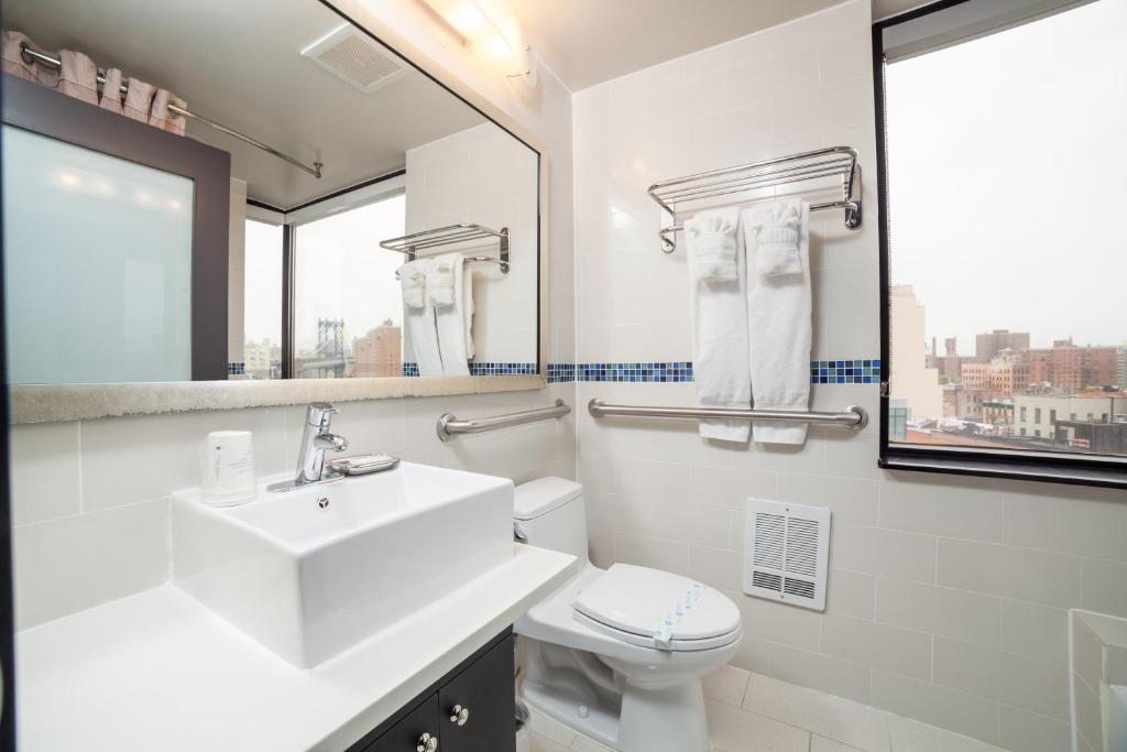 a bathroom with a sink and a toilet and a mirror at Hotel Richland LES in New York