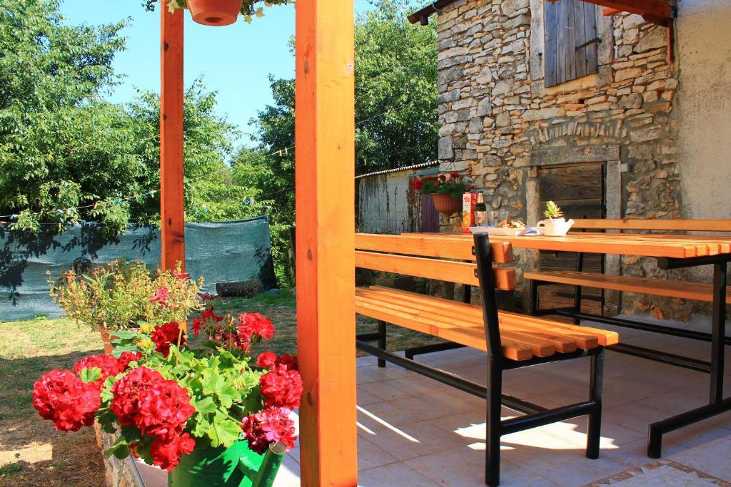a wooden bench and a table and flowers on a patio at Apartment Fuma in Marčana
