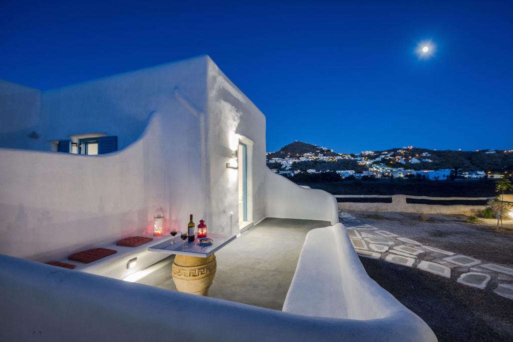 a white house with a table on a balcony at night at Glaros Hotel (By The Sea) in Ios Chora