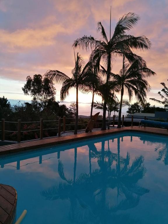 a swimming pool with palm trees and a sunset at Ti kaz Orion in Les Avirons