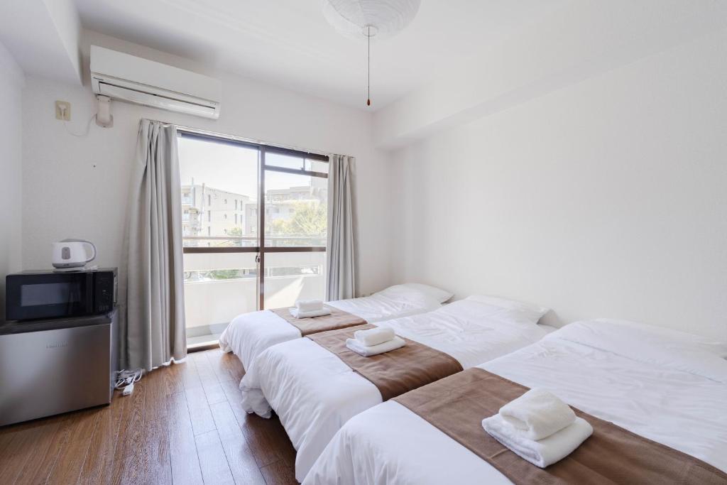 two beds in a room with a large window at Minami-Ohashi Good Place House in Fukuoka