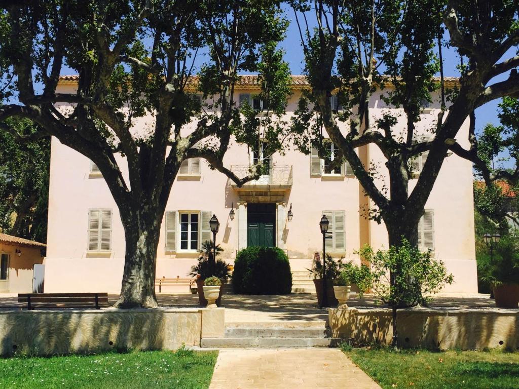 イエールにあるLe château des Angladesの目の前に木々が植えられた白い家