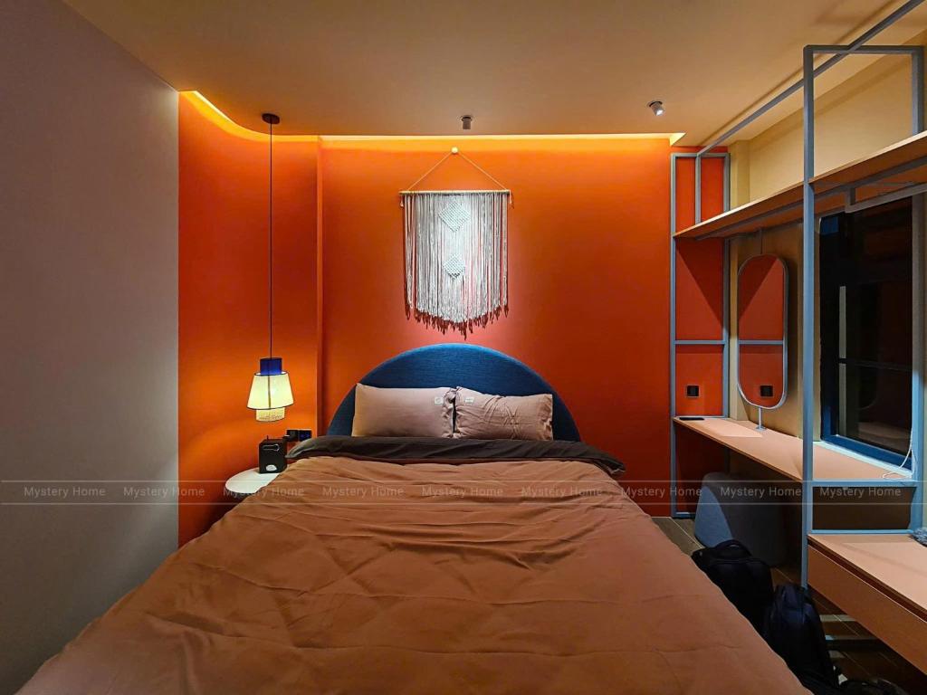a bedroom with a bed with an orange wall at MYSTERY HOME - NOVAWORLD PHAN THIET 3BR 120m2 in Bình Tú