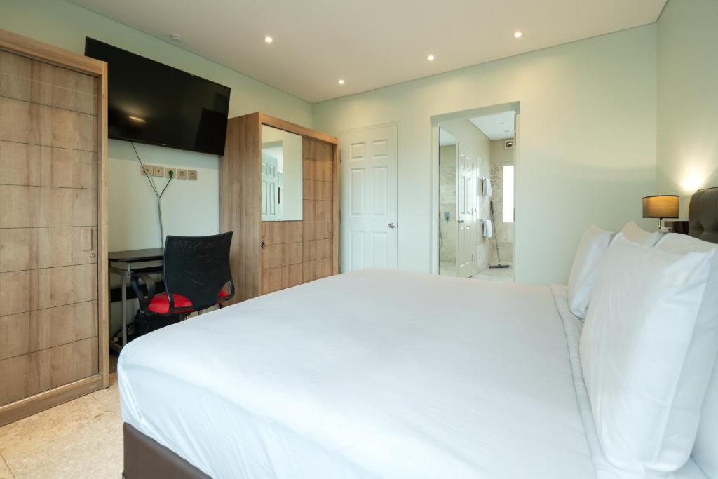 a bedroom with a large white bed and a desk at Mirah Villas in Denpasar