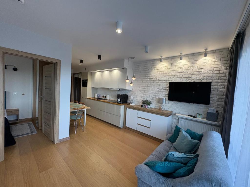 a living room with a couch and a kitchen at Triventi Mountain Residence Apartament Miętowy Zakątek in Karpacz