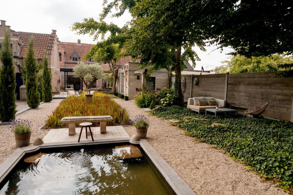 a garden with a pond with a bench and a table at B&b kleinen bosch in Beveren