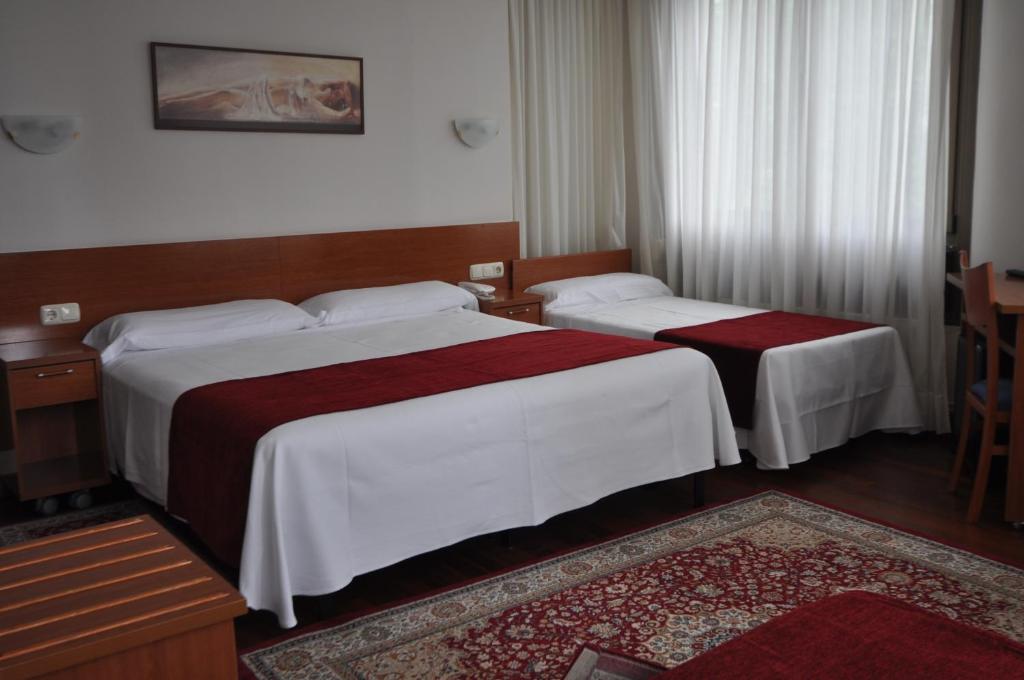 a hotel room with two beds and a table at Pension Alameda in San Sebastián