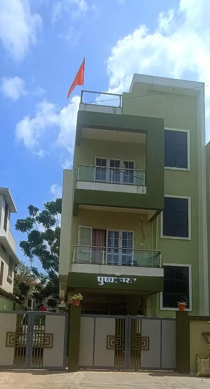 a green building with a flag on top of it at Pushpchhaya Home Stay in Nashik