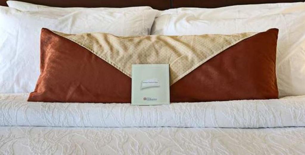 a book sitting on top of a bed with pillows at Hilton Garden Inn Palmdale in Palmdale