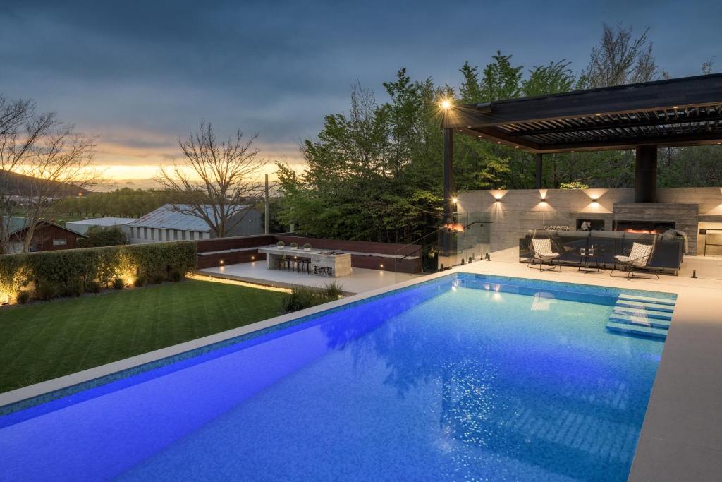 una grande piscina blu in un cortile con pergolato di Bridle Path Retreat - Modern Private Luxury a Christchurch