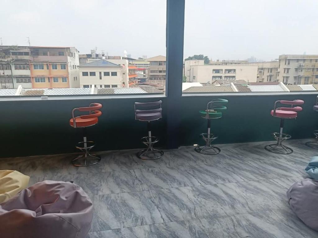 a room with three chairs and a large window at RoXx Social Hostel in Bangkok