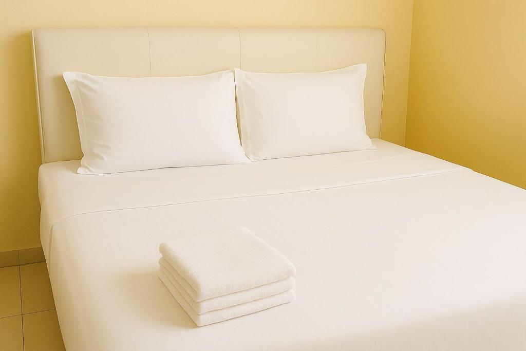 a white bed with a pile of towels on it at T1 Stay Manila-Near NAIA Manila Airport and PITX in Manila