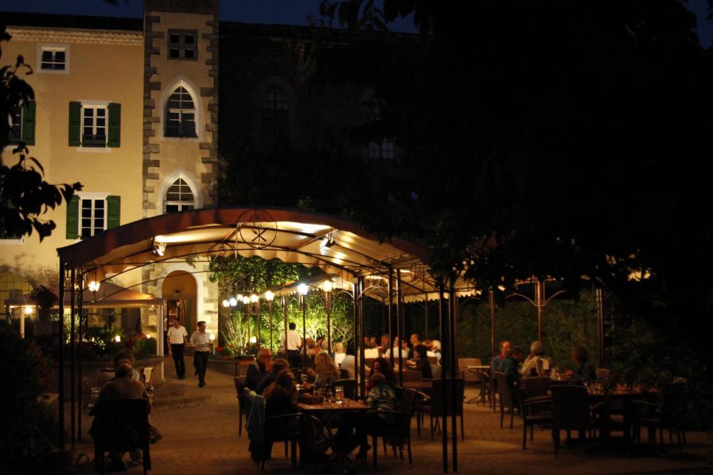 a restaurant with people sitting at tables at night at Hotel Carmel in Les Vans