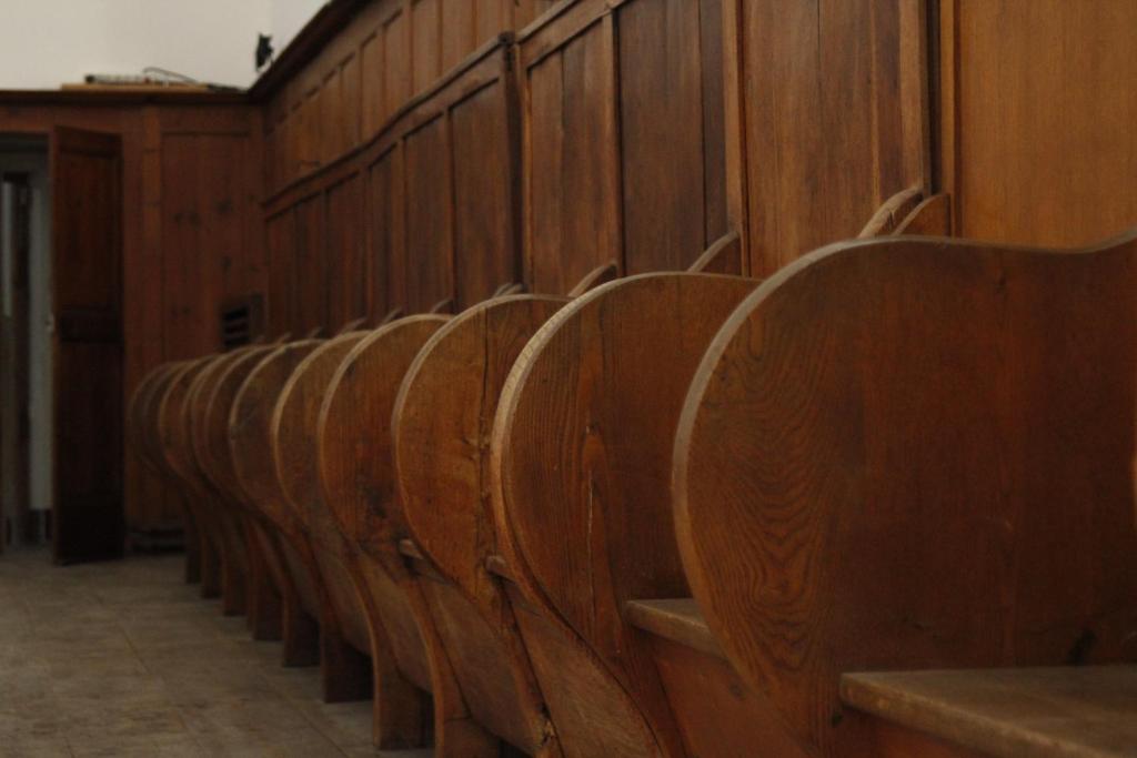 a row of wooden pews in a courtroom at Hotel Carmel in Les Vans