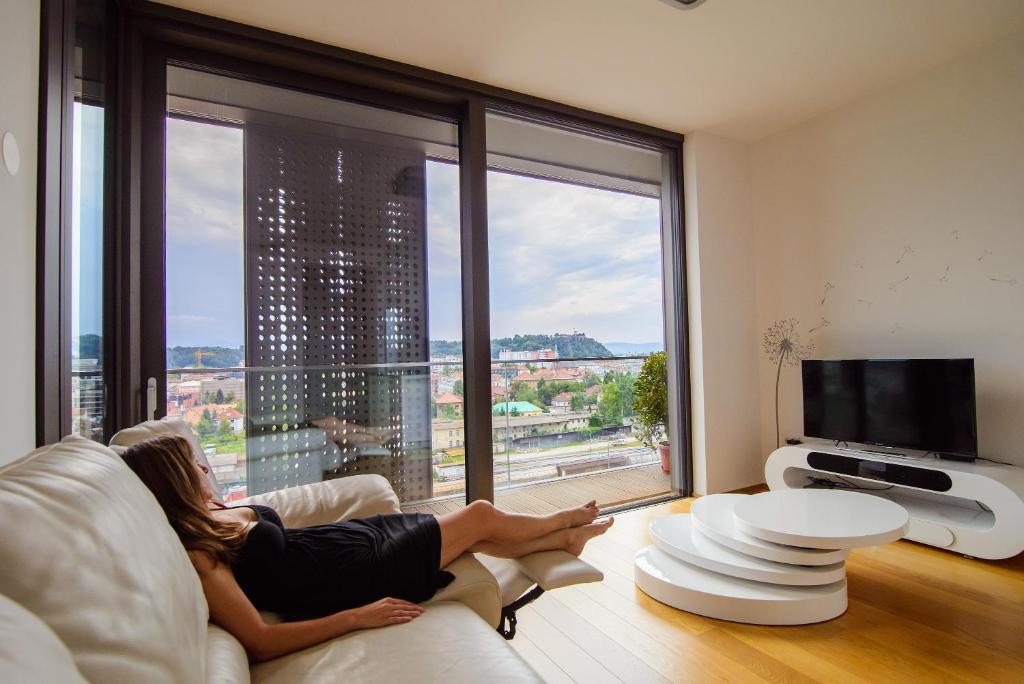 a woman laying on a couch in a living room with a window at Slovenia Crib in Ljubljana