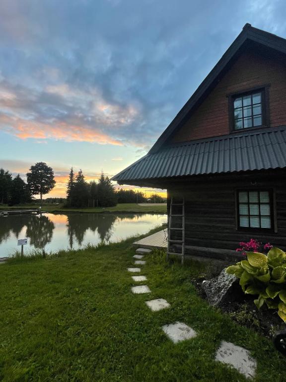 a house with a pond next to a building at Loghouse by the lake in Viljandi