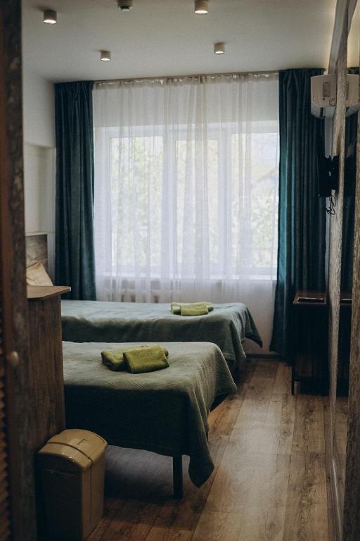 two beds in a room with a window at 7 Nebo in Almaty