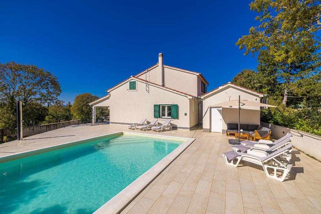 una villa con piscina di fronte a una casa di Holiday house VILLA ANTON with private pool a Kras