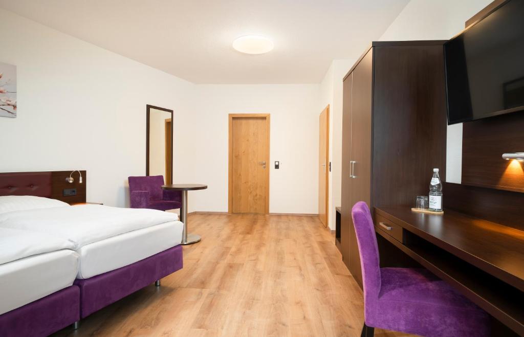 ラムパートハイムにあるates Hotel Lampertheim by AURUMのベッドルーム1室(ベッド1台、デスク、紫色の椅子付)