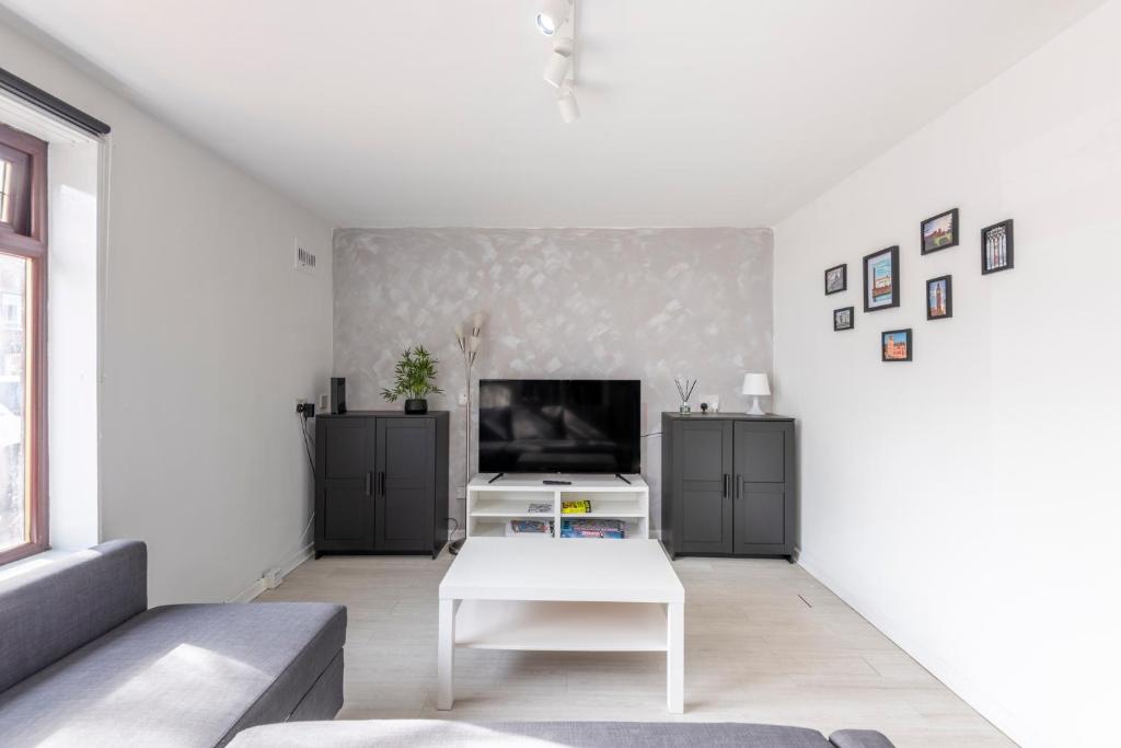 a living room with a tv and a white table at Spacious 2br Near Queens Uni & City Centre in Belfast
