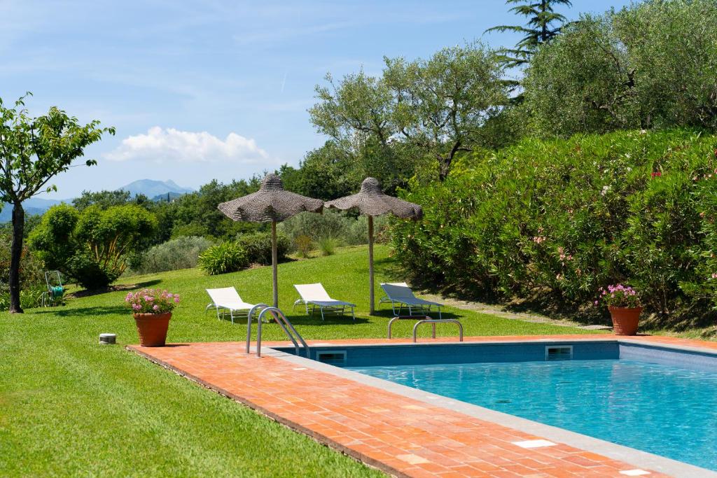 a swimming pool with two umbrellas and two chairs at Bertolli Villas in Matraia