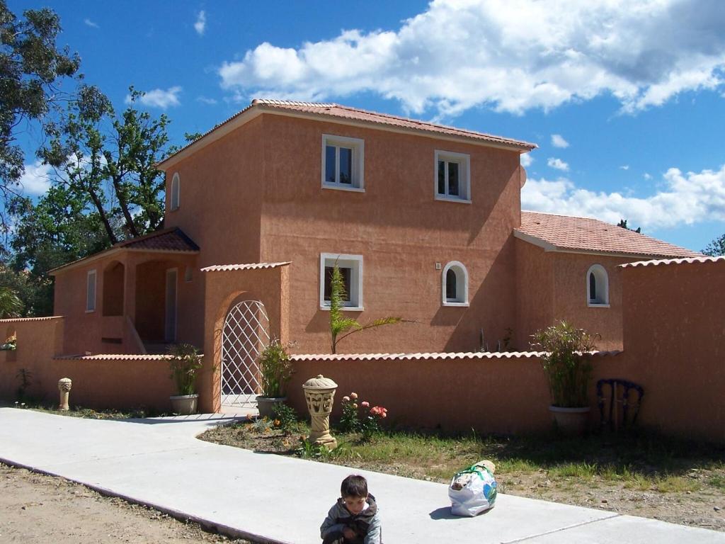 un niño sentado en la acera delante de una casa en Cosy holiday home in Tuscany with shared swimming pool, en San Casciano in Val di Pesa