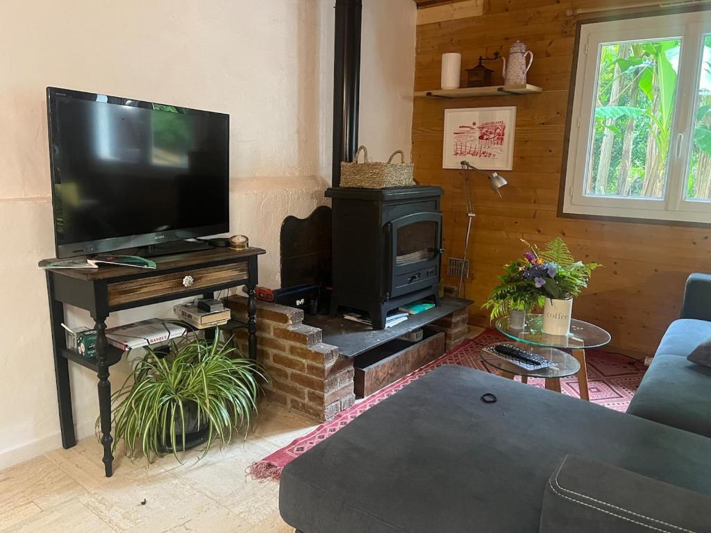 a living room with a television and a stove at Maisonnette deux chambres au fameux PAS DE ROLAND in Itxassou