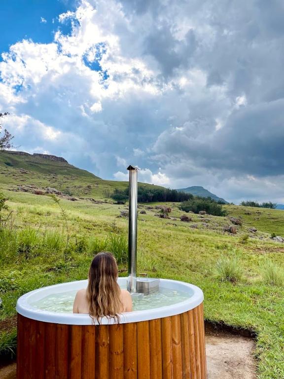 a woman in a hot tub in a field at Sani Lodge & Cottages in Sani Pass