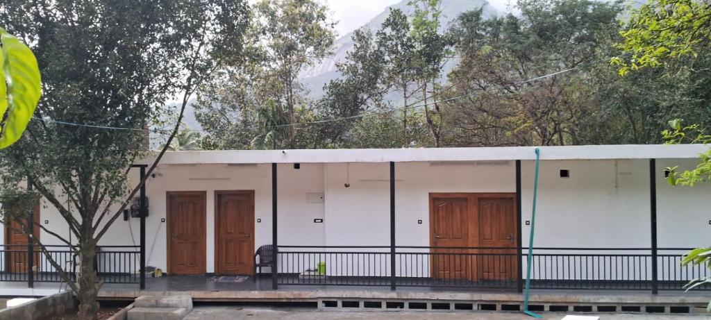 um prédio com portas marrons e árvores ao fundo em eden homestay em Munnar