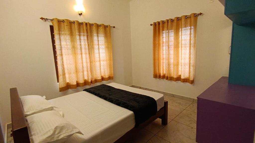 a bedroom with a bed and two windows at Dolmens castle in Marayoor