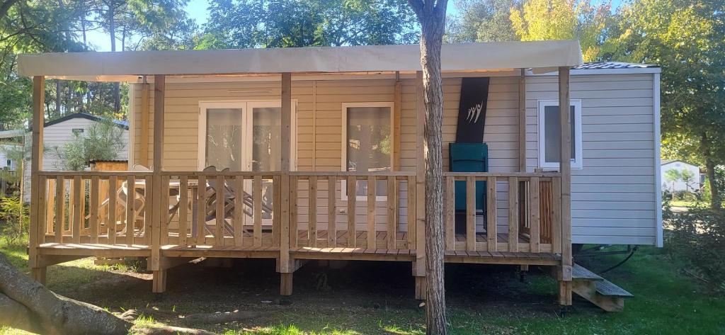 a house with a large deck with a porch at Mobil-home 5 pers climatisé - Plage et forêt - Camping Les Oyats Seignosse in Seignosse