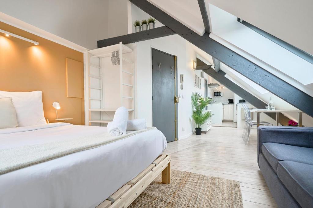 ein Schlafzimmer mit einem großen Bett und einer blauen Couch in der Unterkunft Studio mansardé à deux pas de la Citadelle in Lille