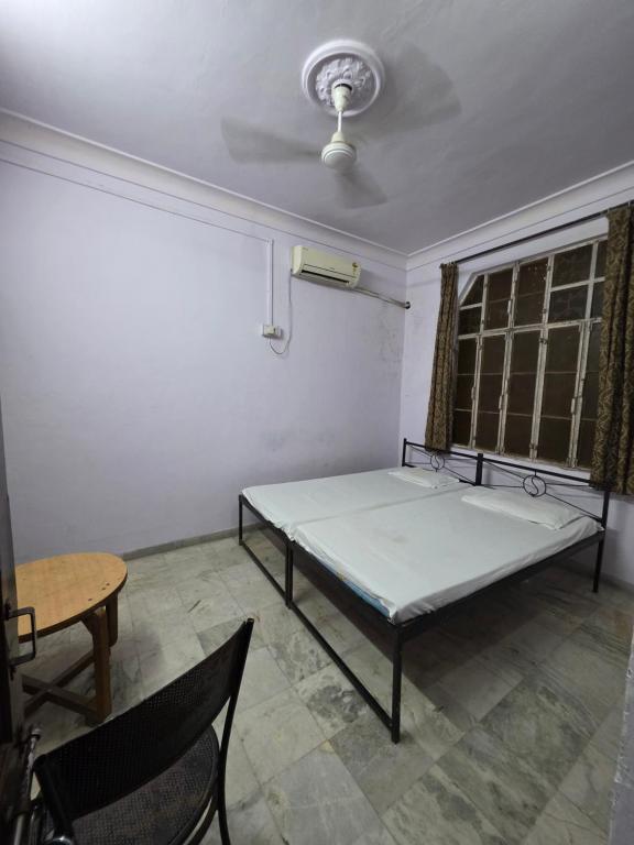 a room with a bed and a table and a window at Sharib House in Ajmer