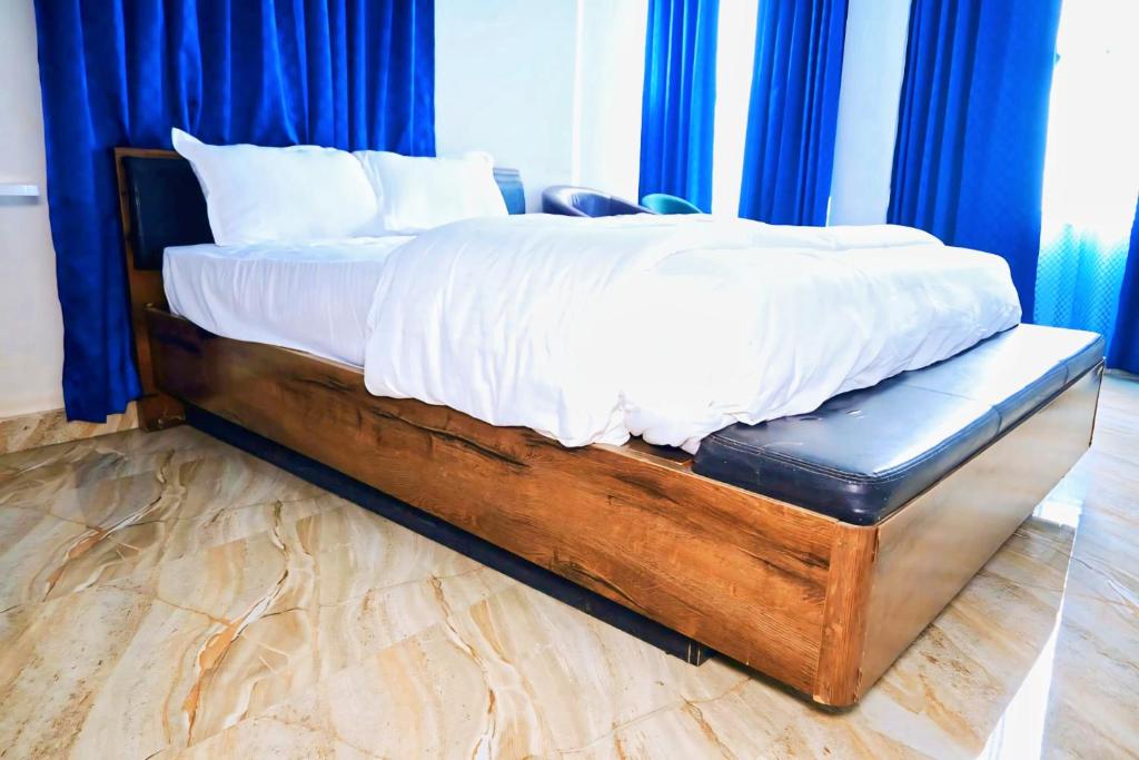 a bed with white sheets on it with blue curtains at Pandooi Prasth, Patna in Patna