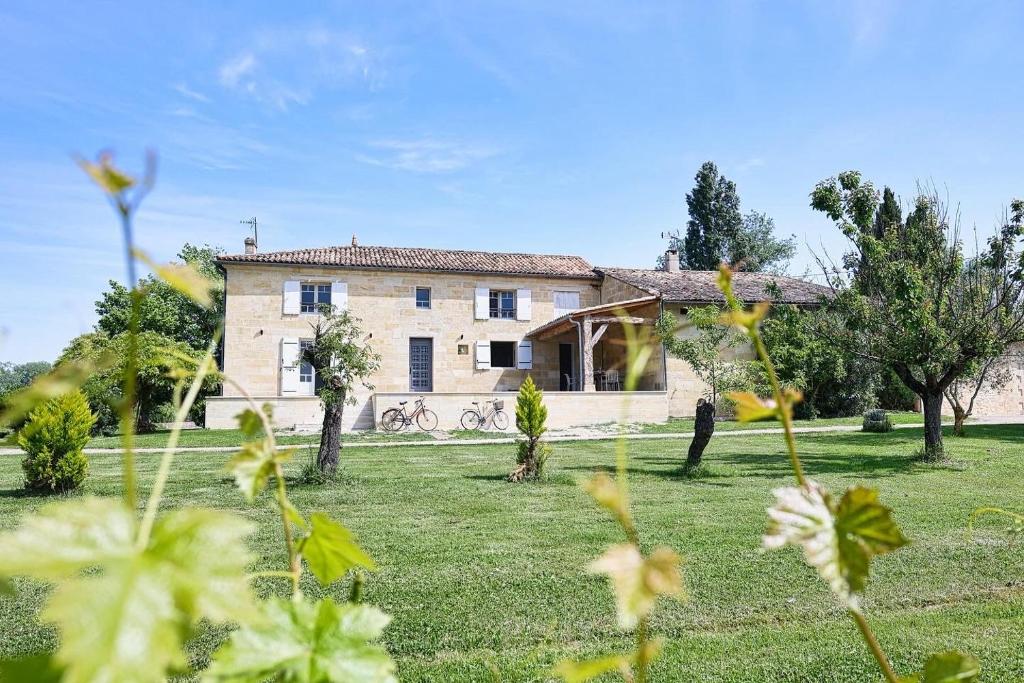 a large stone house in a field with trees at Logis de Belle Rive in Saint-Sulpice-de-Faleyrens