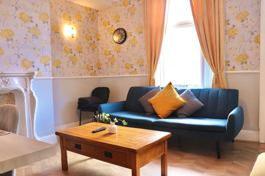 ein Wohnzimmer mit einer blauen Couch und einem Couchtisch in der Unterkunft Comfortable 2 Bed Property with garden - Parking in Hunslet